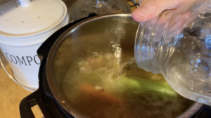 adding water to instant pot of bones and veggies