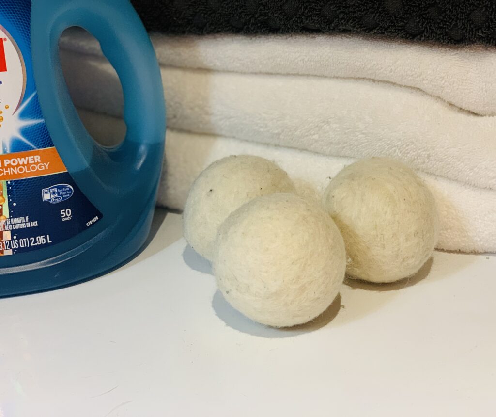 three wool dryer balls next to laundry detergent